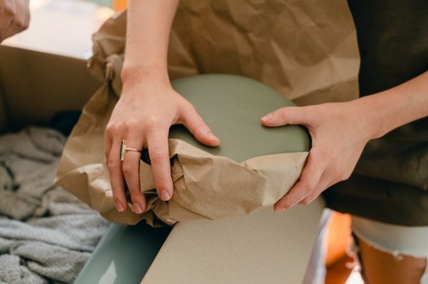 Person putting a dish in wrapping paper.