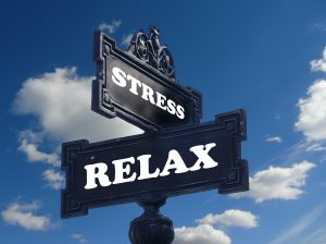 Street signs against the sky with STRESS and RELAX written on them.