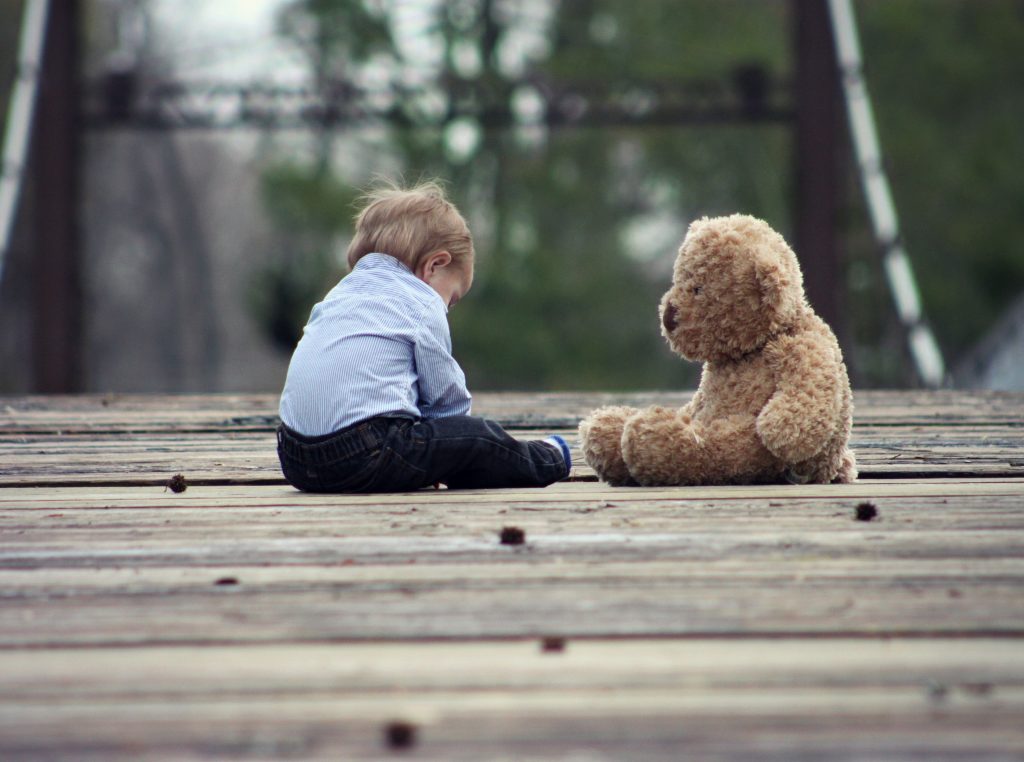 A kid playing with a teddy bear